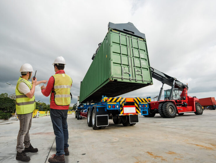 forklift lifting on the container to the trailer in yard, under foreman control in charge